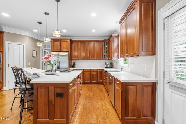 3821 Falls River Ave, Raleigh, NC 27614 - kitchen featuring appliances with stainless steel finishes, light wood-style floors, a breakfast bar area, light countertops, and ornamental molding