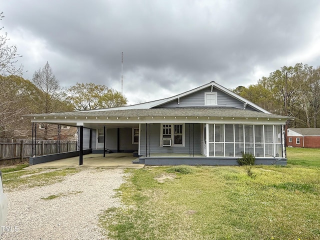 view of front of house featuring roof with shingles, an attached carport, fence, a front lawn, and gravel driveway