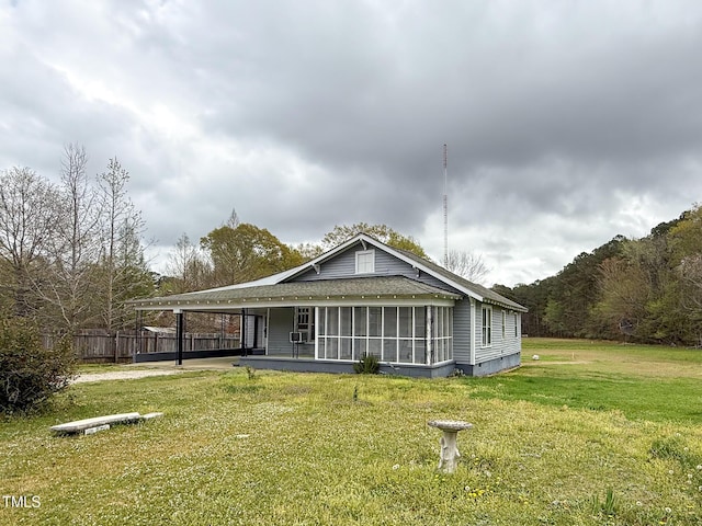 exterior space with a sunroom, roof with shingles, fence, a carport, and a lawn