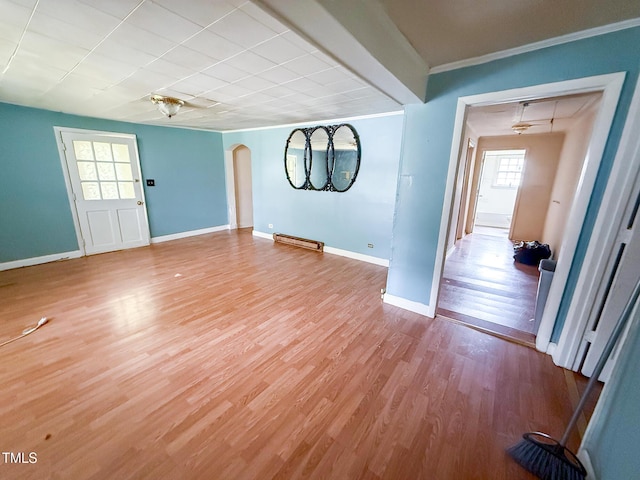 interior space with a baseboard heating unit, a healthy amount of sunlight, light wood finished floors, and baseboards