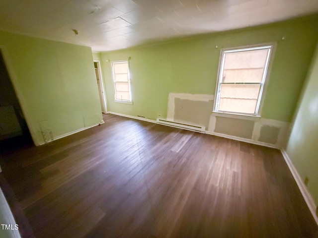 spare room with dark wood-style flooring, baseboards, and baseboard heating