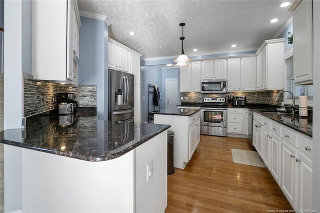 6826 Surrey Rd, Fayetteville, NC 28306 - kitchen with white cabinets, a peninsula, stainless steel appliances, a sink, and light wood-style floors