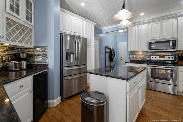 6826 Surrey Rd, Fayetteville, NC 28306 - kitchen featuring crown molding, wood finished floors, beverage cooler, stainless steel appliances, and white cabinets