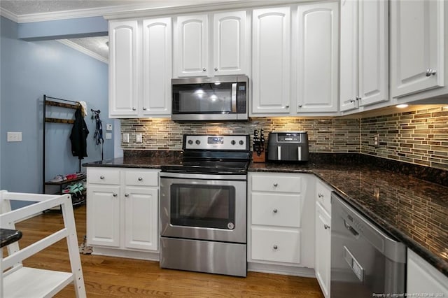 6826 Surrey Rd, Fayetteville, NC 28306 - kitchen featuring white cabinetry, crown molding, light wood-type flooring, decorative backsplash, and appliances with stainless steel finishes