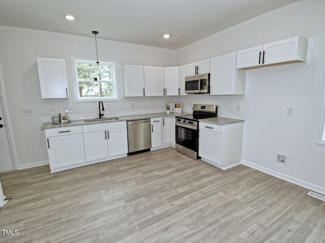 kitchen with visible vents, white cabinets, a sink, light wood-type flooring, and appliances with stainless steel finishes