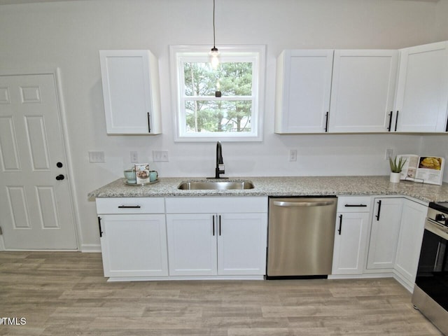 kitchen with white cabinets, a sink, light wood finished floors, light stone countertops, and stainless steel appliances