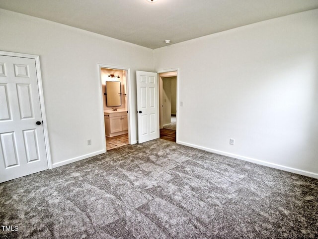 unfurnished bedroom featuring baseboards, connected bathroom, and carpet