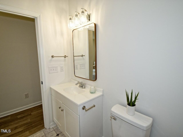 bathroom with toilet, vanity, and baseboards