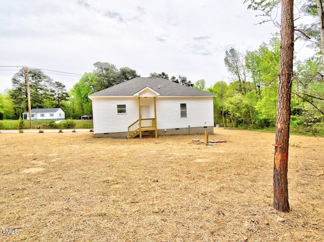 rear view of property with crawl space and roof with shingles