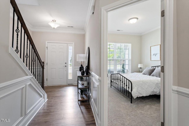 entrance foyer featuring crown molding, dark wood-style flooring, stairs, and a wainscoted wall