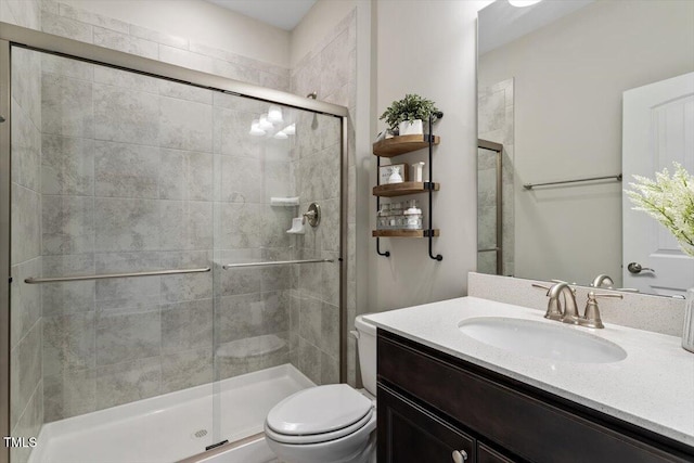 bathroom with vanity, a shower stall, and toilet
