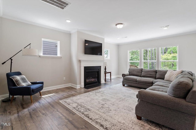 living room featuring crown molding, baseboards, visible vents, and a fireplace with flush hearth