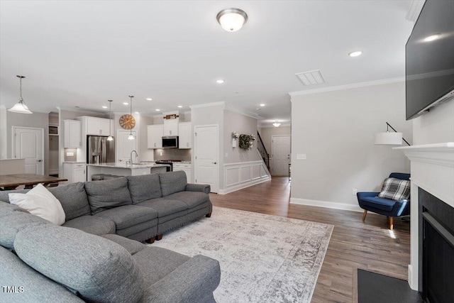 living room featuring crown molding, recessed lighting, visible vents, and light wood-style flooring