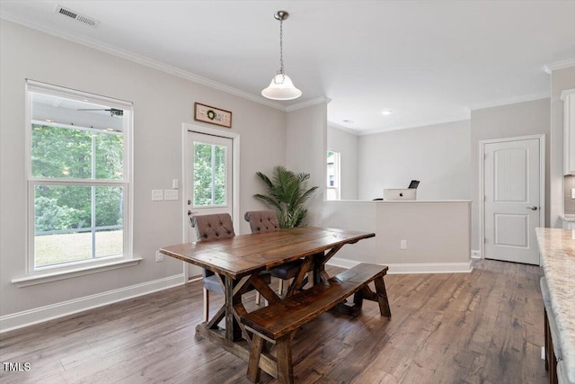 dining area with crown molding, baseboards, visible vents, and wood finished floors