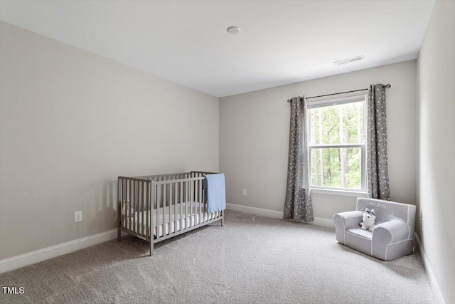 carpeted bedroom with baseboards, visible vents, and a crib