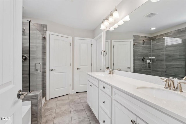 bathroom featuring double vanity, visible vents, a sink, and a stall shower