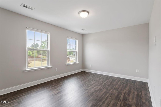 empty room featuring visible vents, baseboards, and dark wood-type flooring