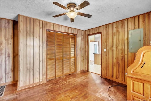 5213 Palmetto Ln, Fayetteville, NC 28304 - unfurnished bedroom with wooden walls, wood finished floors, electric panel, and a textured ceiling