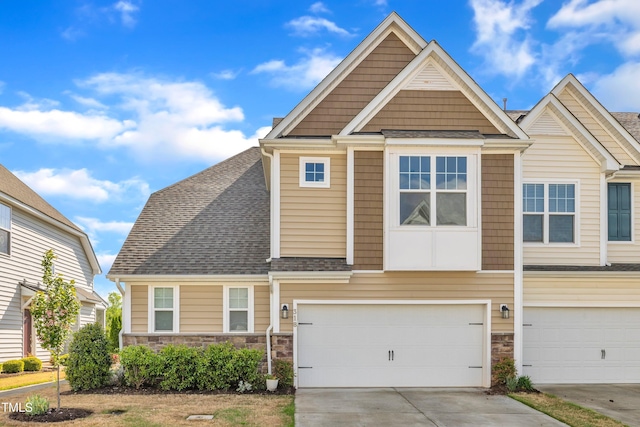 view of front of house with a shingled roof, stone siding, and driveway