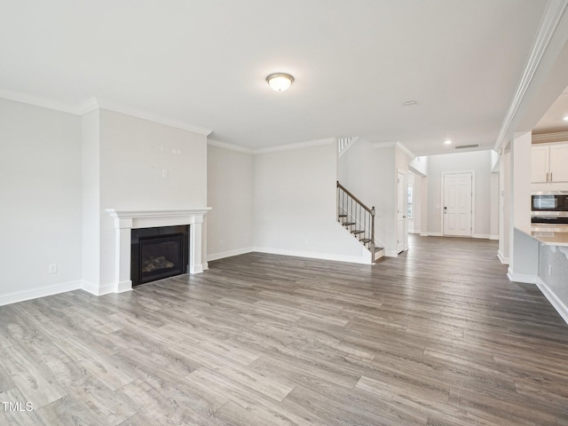 unfurnished living room with a fireplace, wood finished floors, baseboards, and stairs