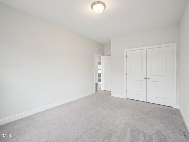 unfurnished bedroom with carpet, a closet, and baseboards