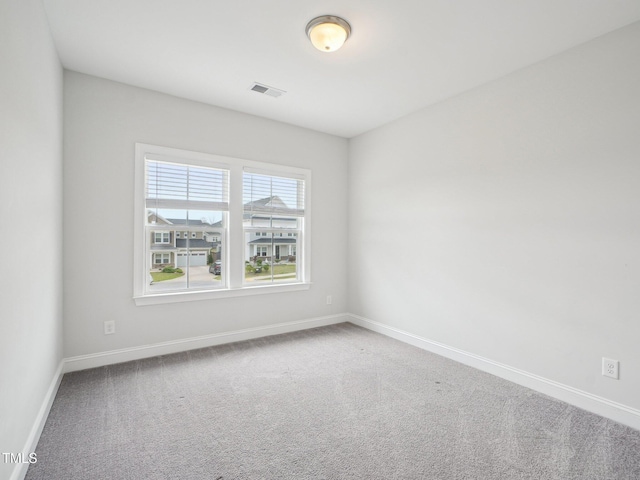 spare room with carpet floors, visible vents, and baseboards