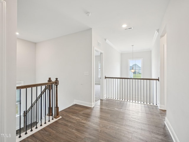 corridor featuring visible vents, crown molding, dark wood-style floors, and an upstairs landing