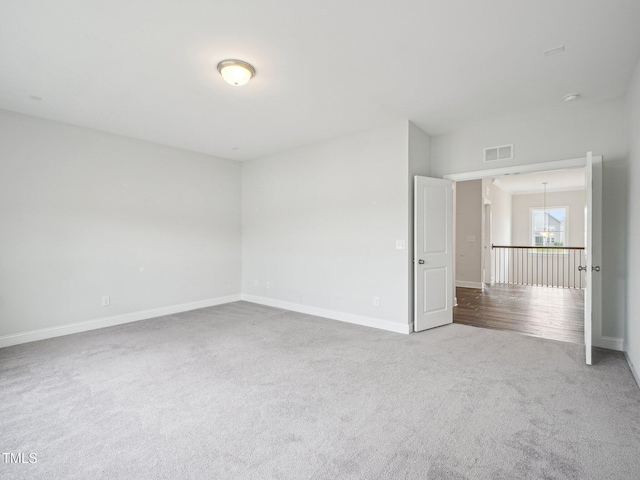 empty room featuring baseboards, a notable chandelier, carpet flooring, and visible vents
