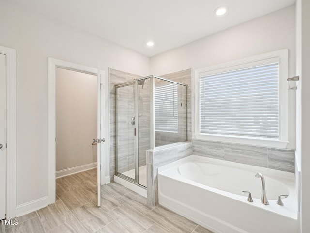 bathroom with a bath, baseboards, recessed lighting, and a shower stall