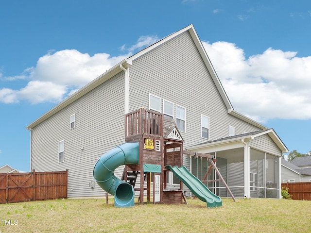 view of jungle gym with fence, a yard, and a sunroom