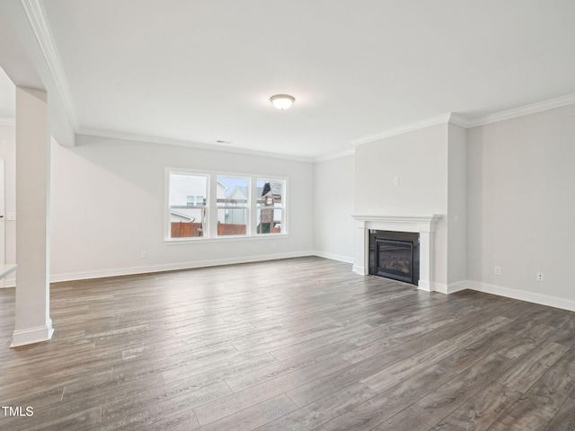 unfurnished living room featuring baseboards, crown molding, a glass covered fireplace, and wood finished floors