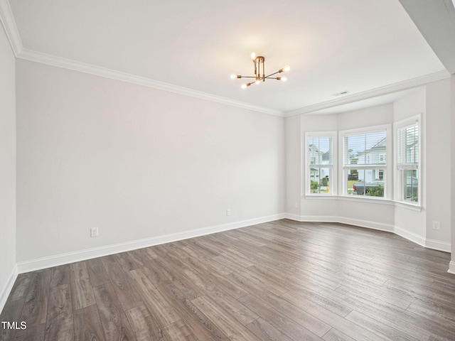 spare room with an inviting chandelier, visible vents, crown molding, baseboards, and dark wood-style flooring