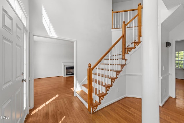 1308 Aspen Falls Ct, Willow Springs, NC 27592 - staircase featuring baseboards, a fireplace with flush hearth, a high ceiling, and wood finished floors