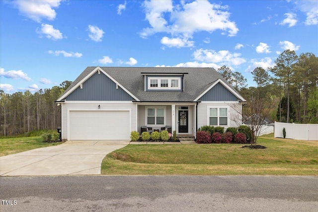 view of front facade with a front yard, a shingled roof, an attached garage, fence, and driveway