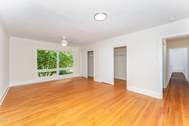 unfurnished bedroom with multiple closets, light wood-style floors, baseboards, and ornamental molding