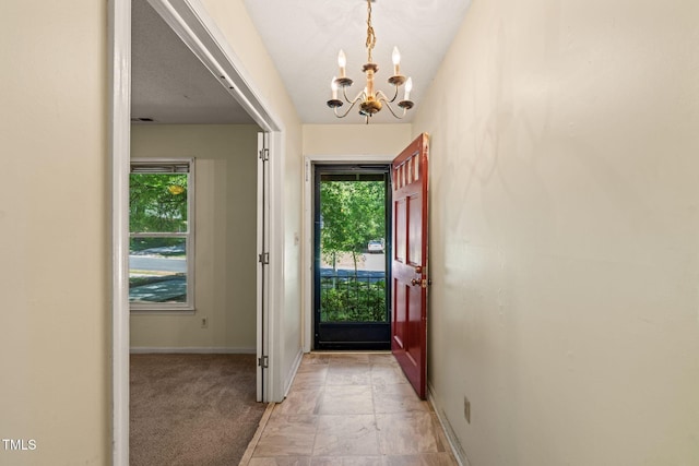 entryway with a chandelier, plenty of natural light, baseboards, and light stone finish flooring