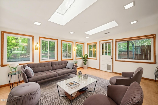 living room featuring a skylight, baseboards, lofted ceiling, and plenty of natural light