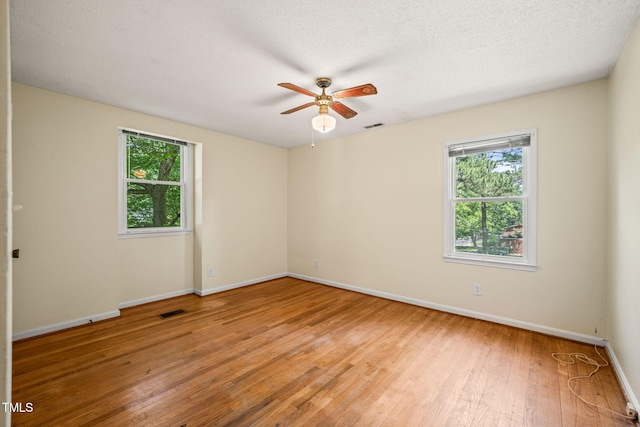 empty room featuring light wood finished floors, ceiling fan, baseboards, and a textured ceiling