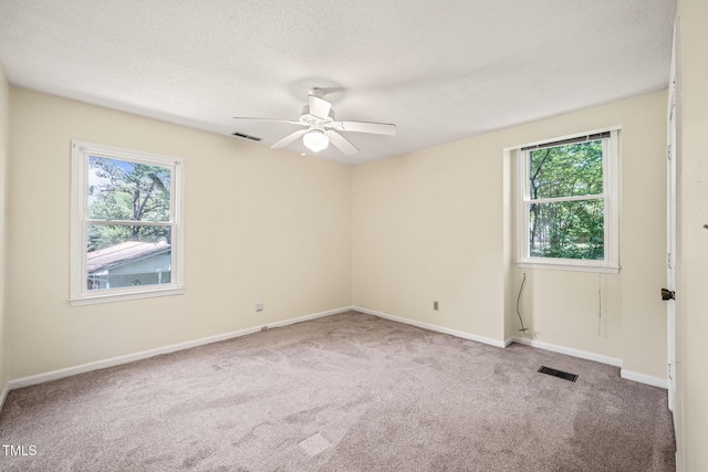 carpeted spare room with healthy amount of natural light, ceiling fan, a textured ceiling, and baseboards