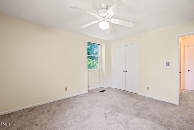 unfurnished bedroom featuring carpet, baseboards, a closet, and a ceiling fan