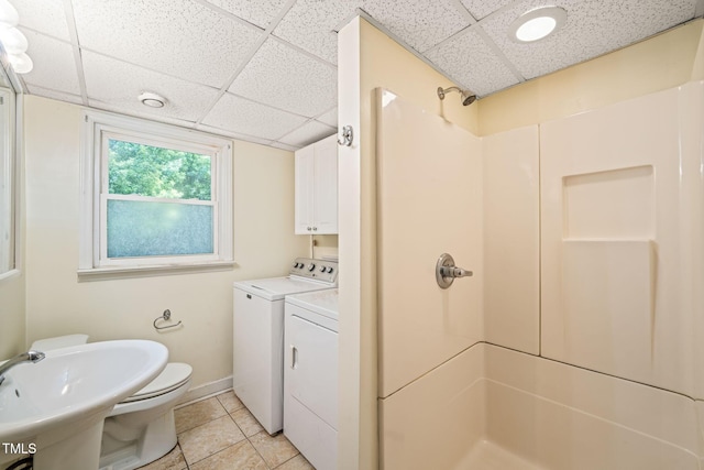 bathroom featuring a drop ceiling, independent washer and dryer, a shower, tile patterned floors, and a sink