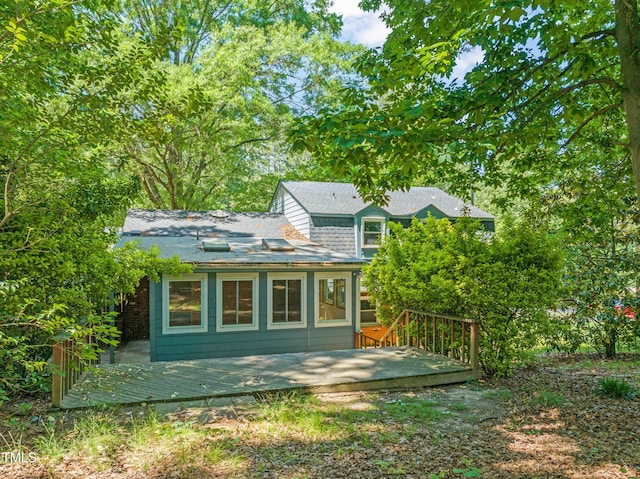 back of property with a wooden deck and roof with shingles