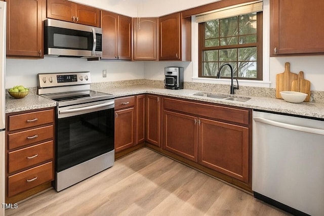 13 Patriot Cir, Durham, NC 27704 - kitchen with appliances with stainless steel finishes, light wood finished floors, and brown cabinetry
