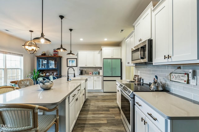 kitchen featuring white cabinetry, a kitchen bar, stainless steel appliances, decorative backsplash, and dark wood finished floors