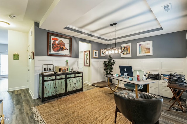home office with a tray ceiling, dark wood finished floors, a wainscoted wall, visible vents, and a decorative wall