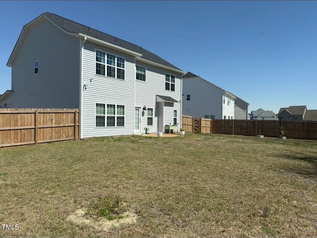 rear view of house featuring a lawn and a fenced backyard