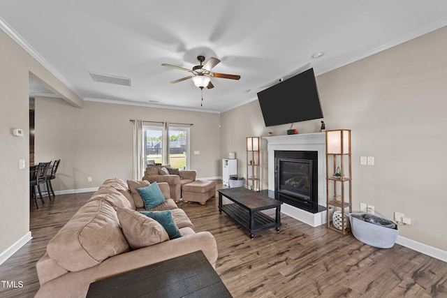living area with a glass covered fireplace, visible vents, a ceiling fan, and wood finished floors