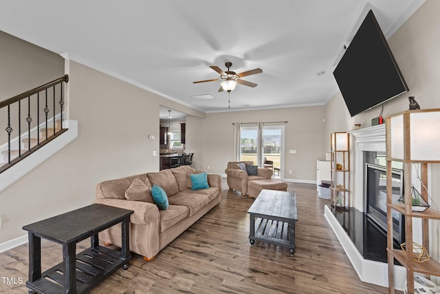 living area featuring wood finished floors, ceiling fan, baseboards, and a glass covered fireplace