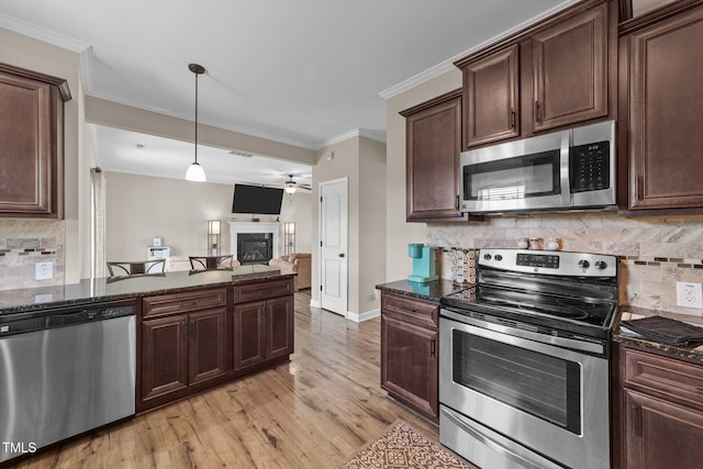 kitchen featuring dark stone countertops, light wood-style floors, dark brown cabinets, and appliances with stainless steel finishes