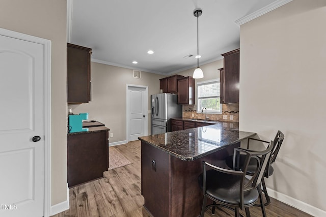 kitchen featuring light wood-style floors, dark brown cabinets, dark stone countertops, stainless steel fridge, and baseboards